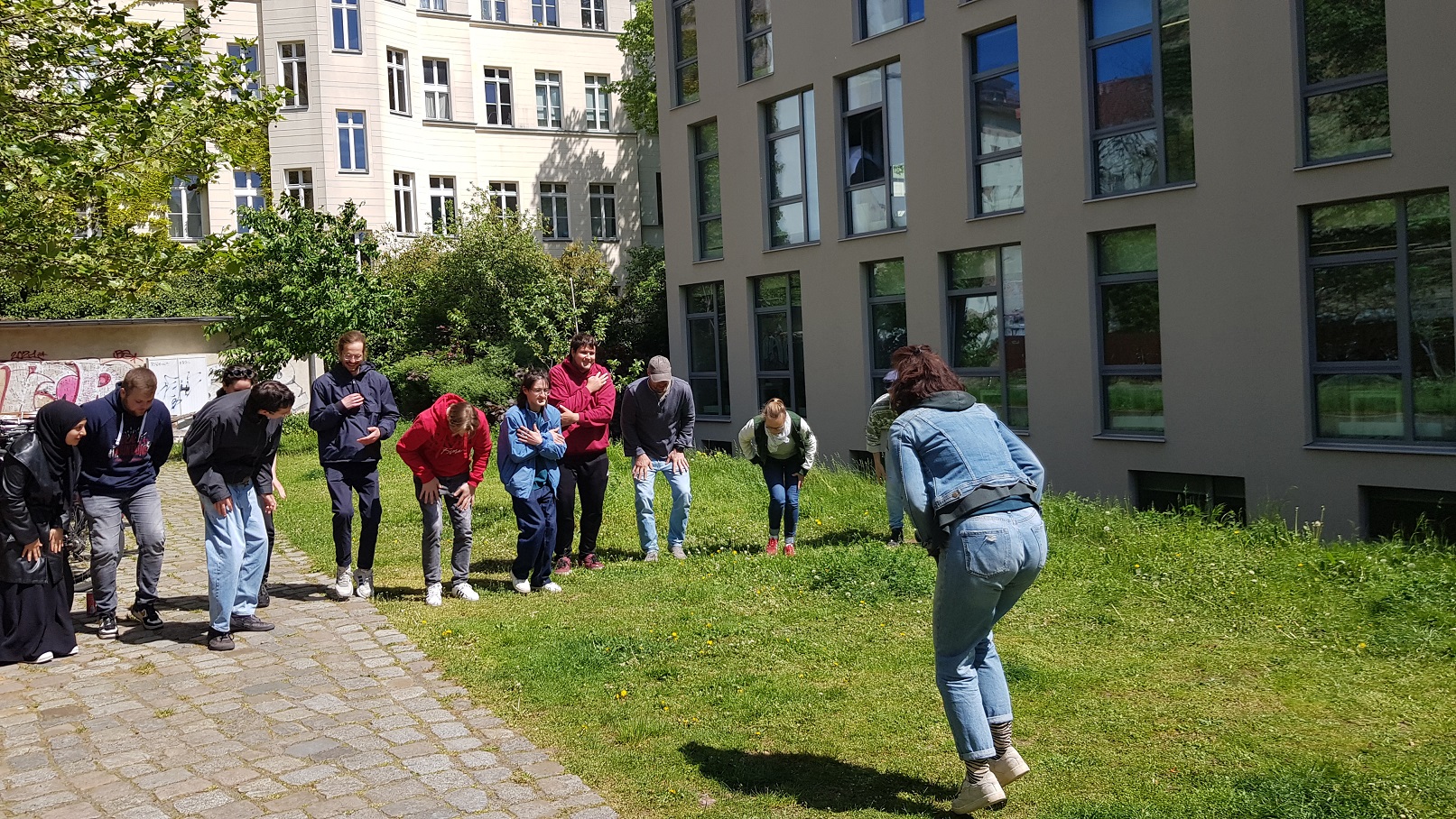 Eine Gruppe von Studierenden machen vor dem Schulgebäude auf dem Gelände Pfefferberg ein Bewegungsspiel.
